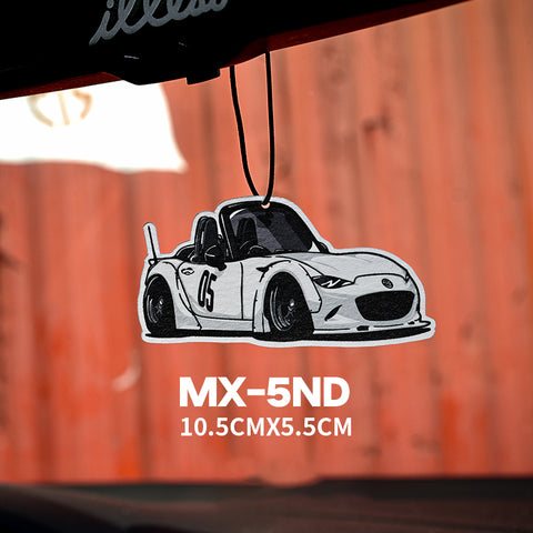 Car air freshener shaped like a white sports car with black details, labeled 'MX-5ND', hanging from a hook.