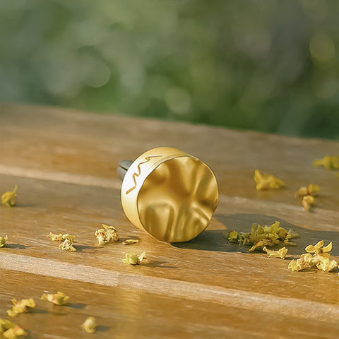 Gold circular object on a wooden surface with small yellow flowers