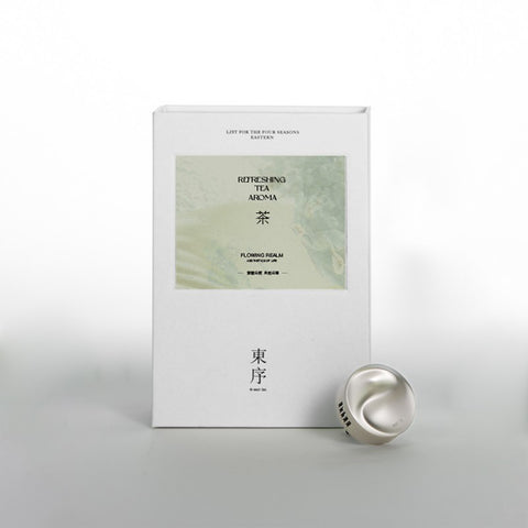 White box with green label and silver object on a light gray background
