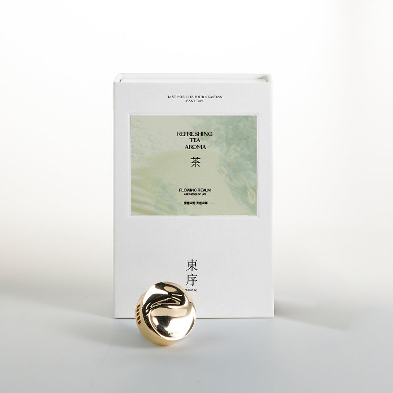 Gold decorative item in front of a white box with green label on a light gray background