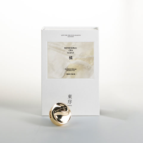 Gold decorative item with a white box labeled 'Ora Scent' on a light gray background