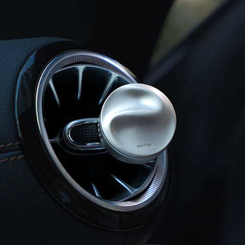 Car air freshener with a metallic finish attached to a car's air vent.
