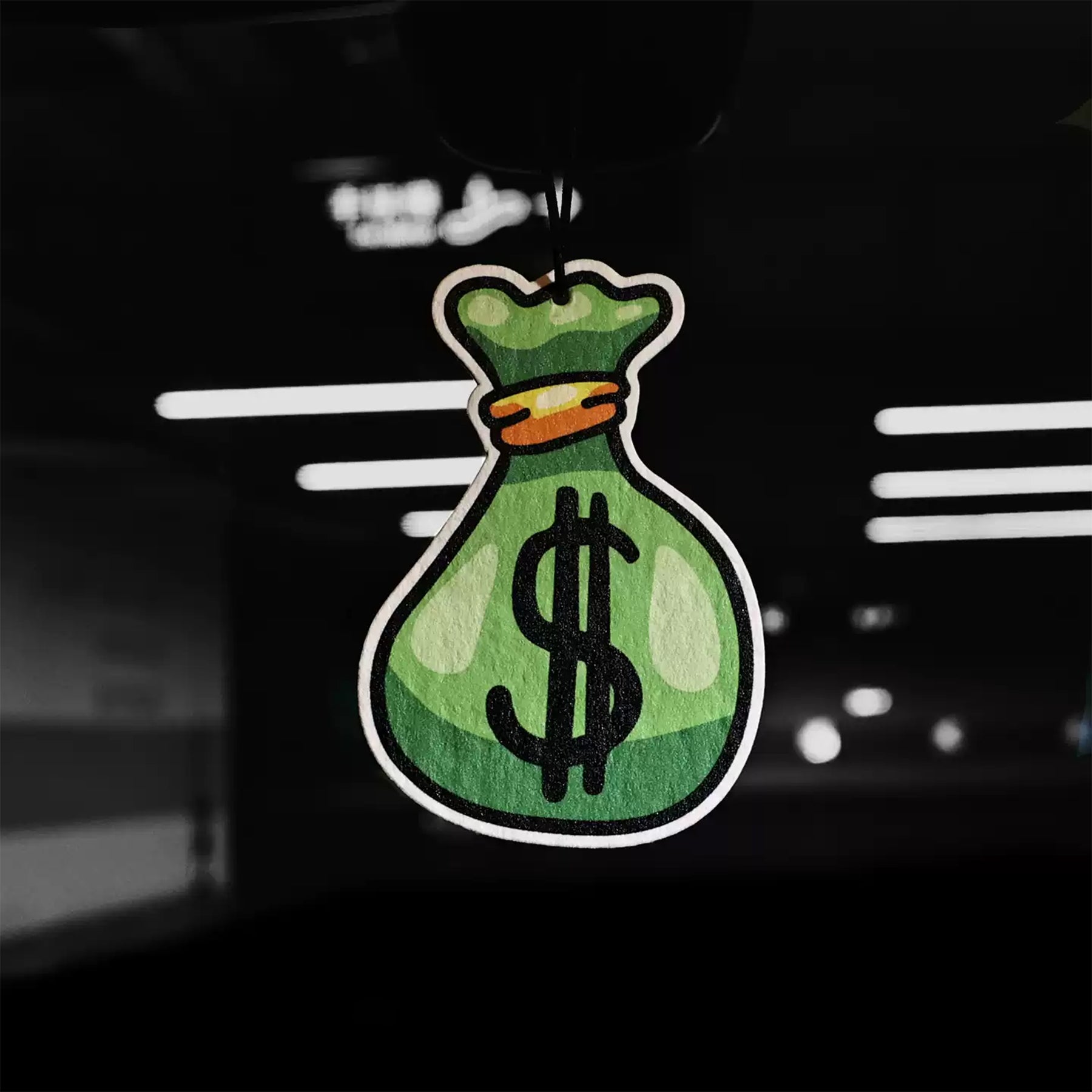 Green money bag with dollar sign car air freshener on a car dashboard