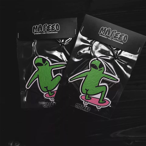 Two Mafeeo alien car fresheners in clear packaging on a black background