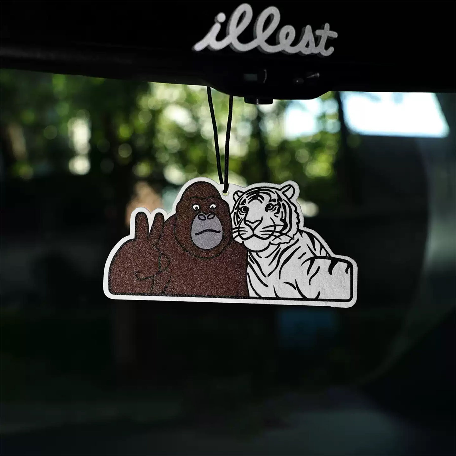 Air freshener with a gorilla and tiger design hanging from a car's rearview mirror.