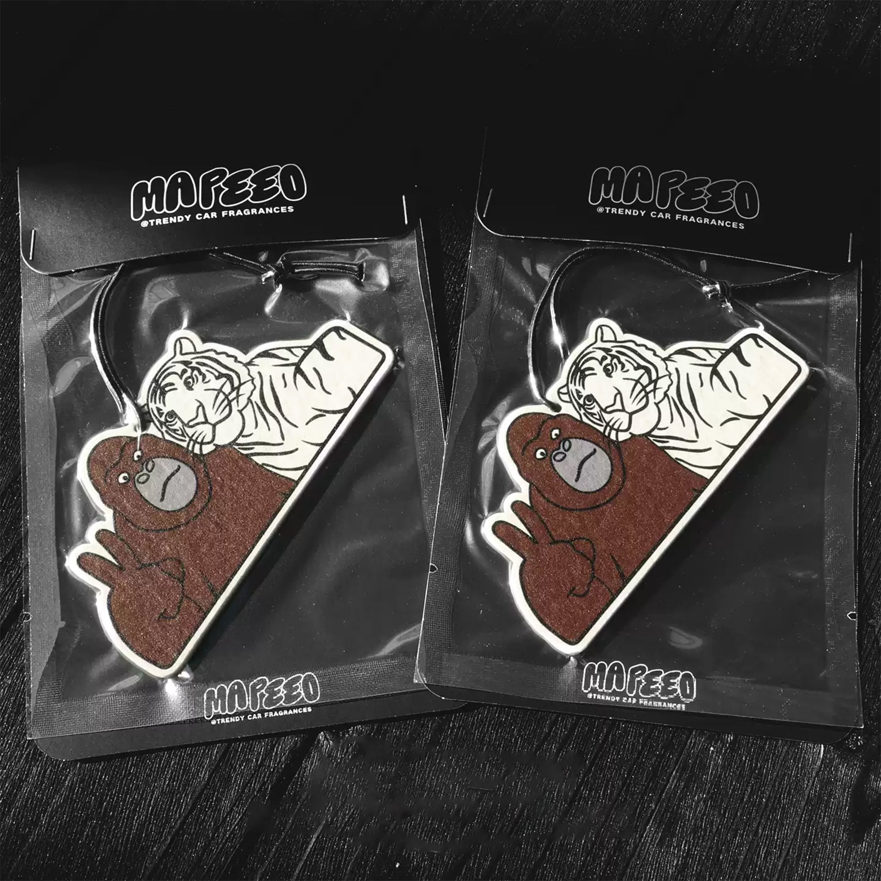 Two Mafeeo car air fresheners with bear and tiger design on a dark surface
