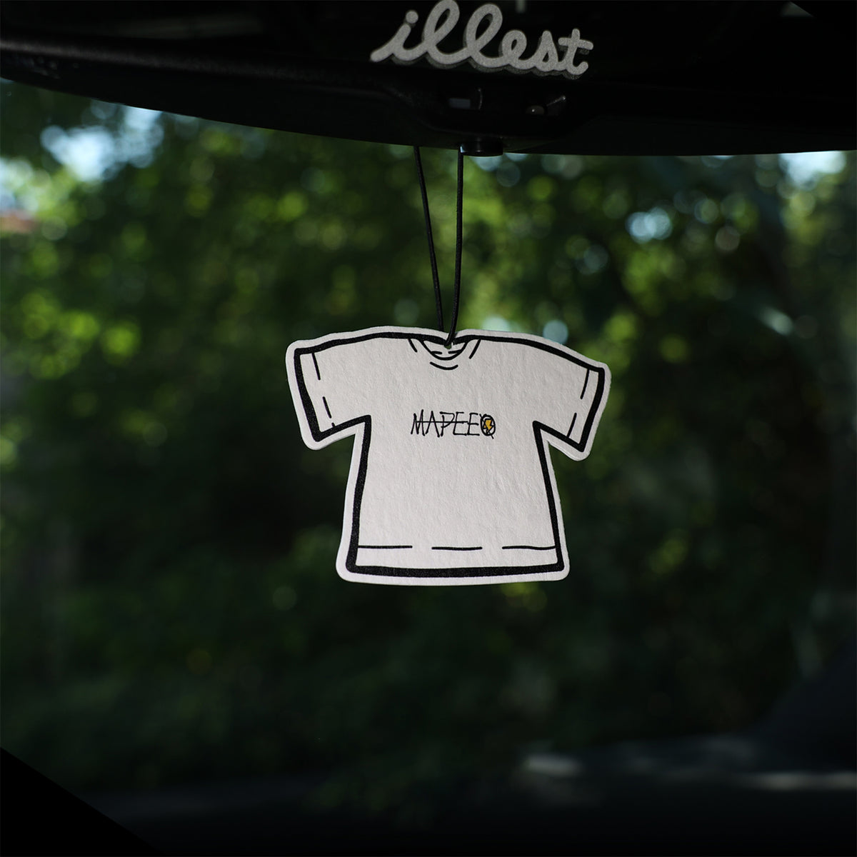 White t-shirt design hanging from a car mirror with 'illest' brand name.