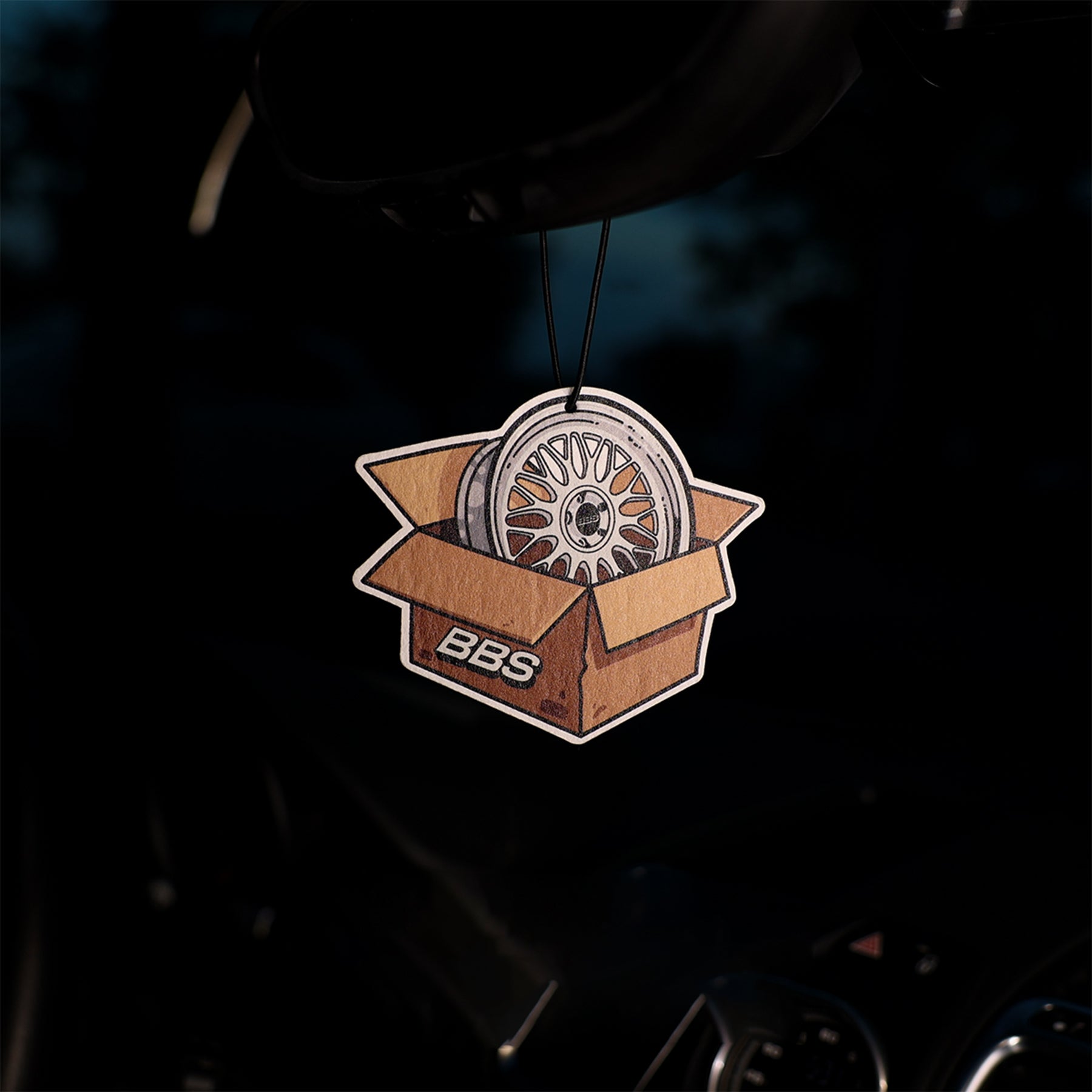 Car air freshener with BBS wheel design in a box on a dark background