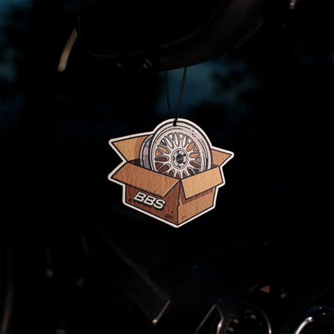 Car air freshener with BBS wheel design in a box on a dark background