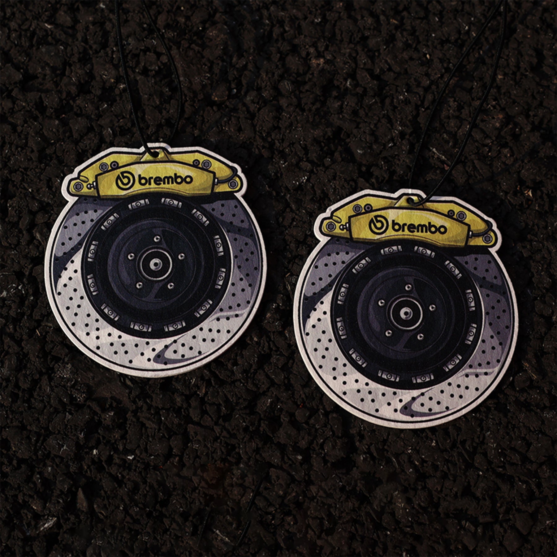 Two brake disc emblems with Brembo logo on a dark textured background
