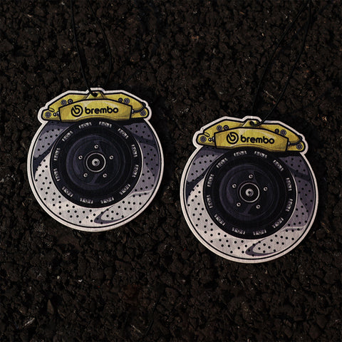 Two brake disc emblems with Brembo logo on a dark textured background