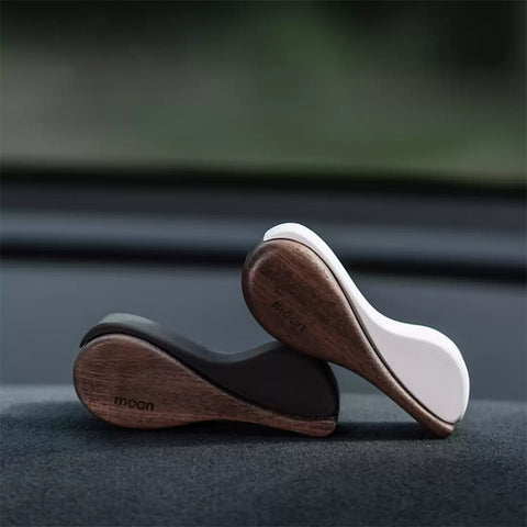 Two shoe insoles, one wooden and one white, on a dark surface with a blurred background.