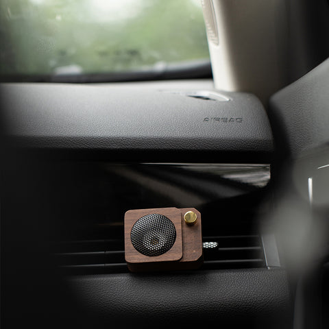 Wooden car air freshener attached to a car's air vent.