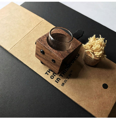 Wooden ring holder with glass on a black surface with brown paper