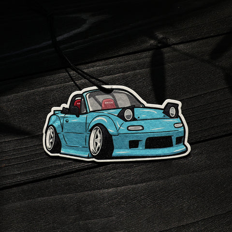 Sticker of a blue car on a dark wooden surface