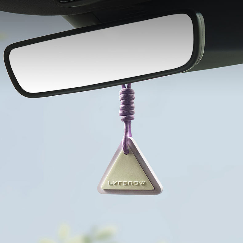 Car air freshener hanging from a car mirror with a blurred outdoor background