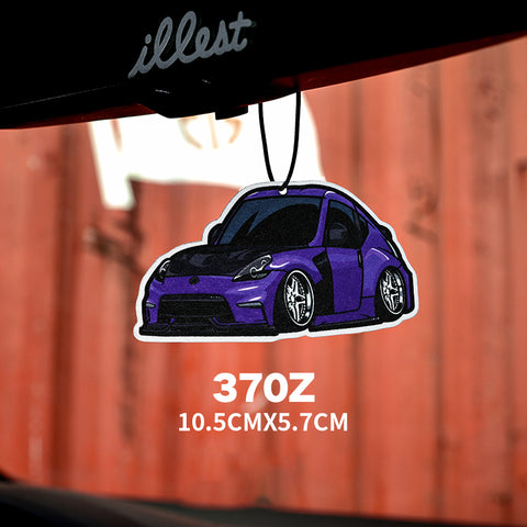 Purple car-shaped air freshener with 'illest' branding against a red metal surface.
